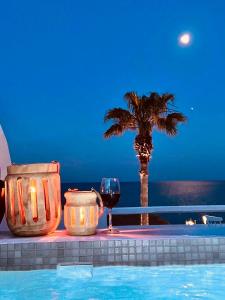 a glass of wine and a palm tree next to a pool at Makris Beach Hotel in Kamari