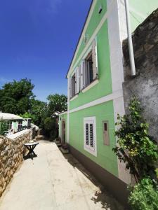 a green and white building with a bench next to it at House Green Point in Grižane