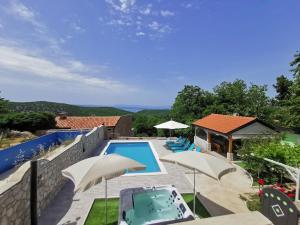 a villa with a swimming pool and a patio with umbrellas at House Green Point in Grižane