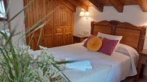 Schlafzimmer mit einem Bett mit lila und rosa Kissen in der Unterkunft Apartamentos El Haya in Cosgaya