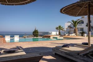 a resort with a swimming pool with chairs and an umbrella at Arkasa Palace in Arkasa