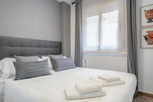 a bedroom with a white bed with towels on it at Inside Barcelona Apartments Salva in Barcelona