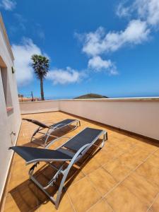 um par de cadeiras numa varanda com uma palmeira em Apartamento La Villa em Valverde