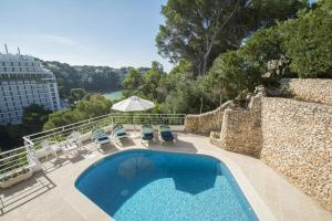 uma piscina com cadeiras e um guarda-sol e um edifício em Miramar I by Sonne Villas em Cala Galdana