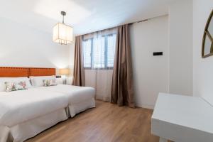 um quarto com uma grande cama branca e uma janela em Apartmentsole - San Pablo em Sevilha