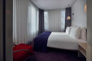 una habitación de hotel con una gran cama blanca y ventana en WestCord Art Hotel Amsterdam 4 stars, en Ámsterdam