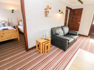 a living room with a leather couch and a bed at Ashford Cottage in Bakewell