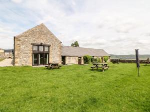 ein Steingebäude mit Picknicktischen im Gras in der Unterkunft Ashford Cottage in Bakewell