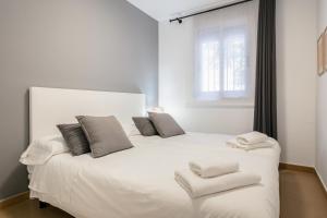 a white bedroom with a large white bed with two pillows at Inside Barcelona Apartments Salva in Barcelona