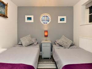 2 Betten in einem Zimmer mit einem Tisch und einem Fenster in der Unterkunft Pass the Keys Charming Fisherman's cottage with stunning sea views in Swansea