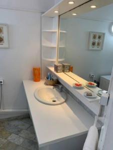 W białej łazience znajduje się umywalka i lustro. w obiekcie 5 min from Orient Bay - perfect condo, Idolem résidence unité 6 - 57 Rue du Mont Vernon 1 w mieście Cul de Sac
