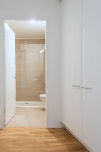 a white bathroom with a shower and a toilet at HITrental Messe Apartments in Basel