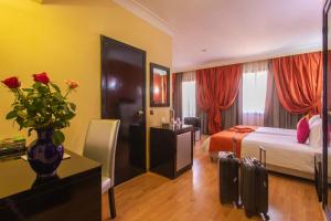 a hotel room with a bed and a vase with roses at Hotel Meriem Marrakech in Marrakesh