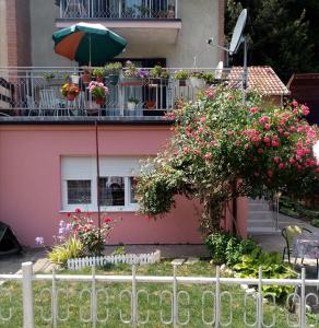 Casa rosa con balcón con flores y sombrilla en Apartman Vesna, en Ovčar Banja
