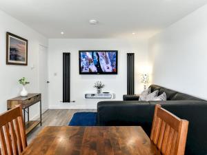 uma sala de estar com um sofá preto e uma mesa em Pass the Keys Newly Renovated Bungalow - Stunning views of Gower em Swansea