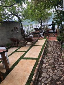 a patio with benches and tables and trees at Rosas Home in Pogradec