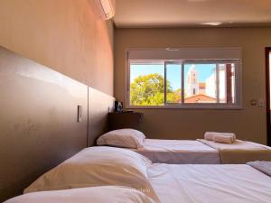 two beds in a room with a window at Pousada Reserva Central in Capitólio +45 photos
