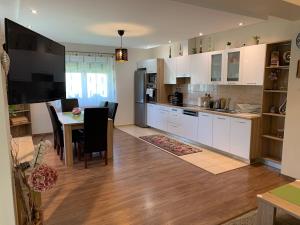 a kitchen with white cabinets and a table with chairs at Villa Eszter in Balatonkeresztúr