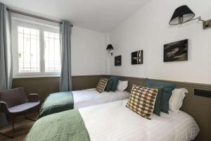 a bedroom with two beds and a chair and a window at Marianne in Paris