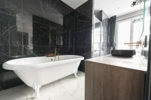 a bathroom with a white tub and black tiles at Marianne in Paris
