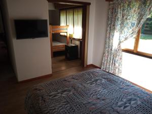 Schlafzimmer mit einem Bett, einem TV und einem Fenster in der Unterkunft Casa Perez in San Martín de los Andes