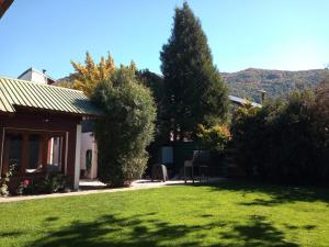 una casa con un patio con césped verde y árboles en Casa Perez en San Martín de los Andes