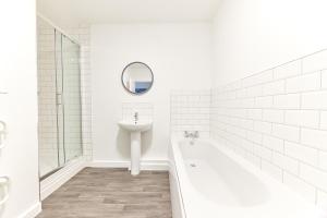 a white bathroom with a sink and a tub and a mirror at Low Lights - Properties Unique in North Shields