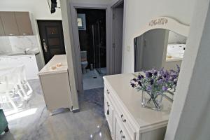 a bathroom with a vase of purple flowers on a counter at Olga's Suite Al Mar in Skala Kallirakhis