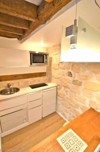 a kitchen with white cabinets and a stone wall at Gallery in Paris