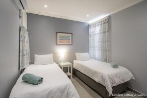 a bedroom with two beds and a window at Twin Tide Duplex in Umdloti