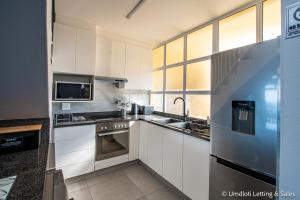 a kitchen with white cabinets and stainless steel appliances at Twin Tide Duplex in Umdloti