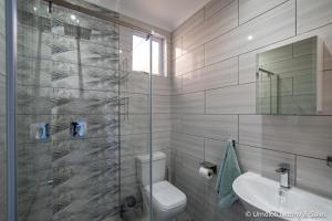 a bathroom with a shower and a toilet and a sink at Twin Tide Duplex in Umdloti +18 photos