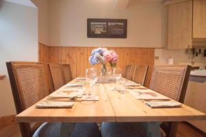 a long wooden table with a vase of flowers on it at Steading Cottage - 50m from the beach in Port Appin