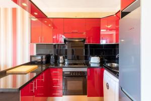 une cuisine rouge avec des comptoirs noirs et des armoires rouges dans l'établissement MEDANO4YOU Mirandas Choice Penthouse, à El Médano