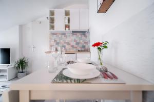 a white kitchen with a table with plates on it at Sweet Loft Apartment (White) in Rijeka center in Rijeka