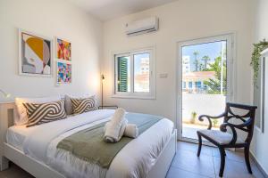 a bedroom with a bed and a chair and a window at Arty Haven - Spacious 3-BR House in Larnaca in Larnaca