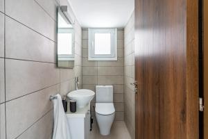 a bathroom with a toilet and a sink and two windows at Arty Haven - Spacious 3-BR House in Larnaca in Larnaka +29 photos