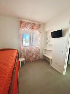 1 dormitorio con 1 cama, ventana y TV en Quinta corrente, en Vieste