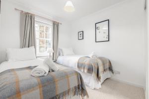 a white bedroom with two beds and a window at Abbey Street - 2 bedroom - Central in St. Andrews