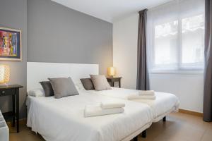 a bedroom with two beds with white sheets and a window at Inside Barcelona Apartments Salva in Barcelona