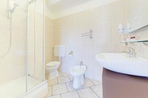 een badkamer met een wastafel, een toilet en een douche bij Hotel Grotto Bagat in Lavena Ponte Tresa