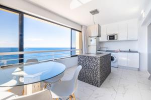 een keuken en eetkamer met een glazen tafel en stoelen bij Torre Levante 22C in Benidorm