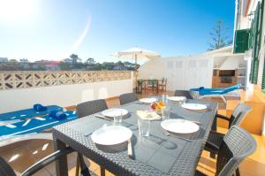 eine Terrasse mit einem Tisch mit Stühlen und einem Sonnenschirm in der Unterkunft Can Tomeu by Sonne Villas in Cala Galdana