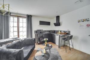 un soggiorno con divano grigio e una cucina di SWEET ANGEL Suite romantique avec SPA a Bruz Altre 13 foto
