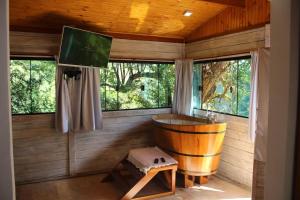 a wooden bathroom with a wooden tub in a room with windows at Jardim Suspenso da Babilônia in Santo Antônio do Pinhal