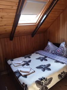 a bed in a wooden room with a window at HANUL VANATORULUI in Gura Humorului