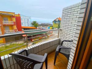 a balcony with two chairs and a view of a city at Apartamentos Pineda in Noja