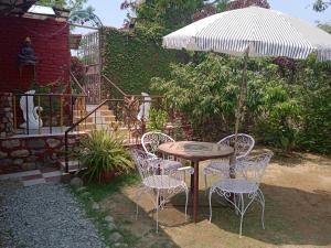 a table and chairs with an umbrella in a yard at Oxygen Homestay in Dehradun