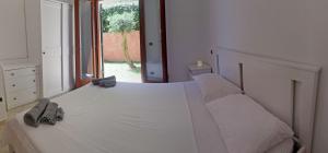 une chambre avec un grand lit blanc avec une fenêtre dans l'établissement Residence Nausicaa, à Santa Teresa Gallura