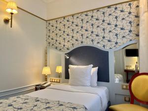 a bedroom with a bed with a blue and white patterned wall at Hôtel Mayfair Paris in Paris